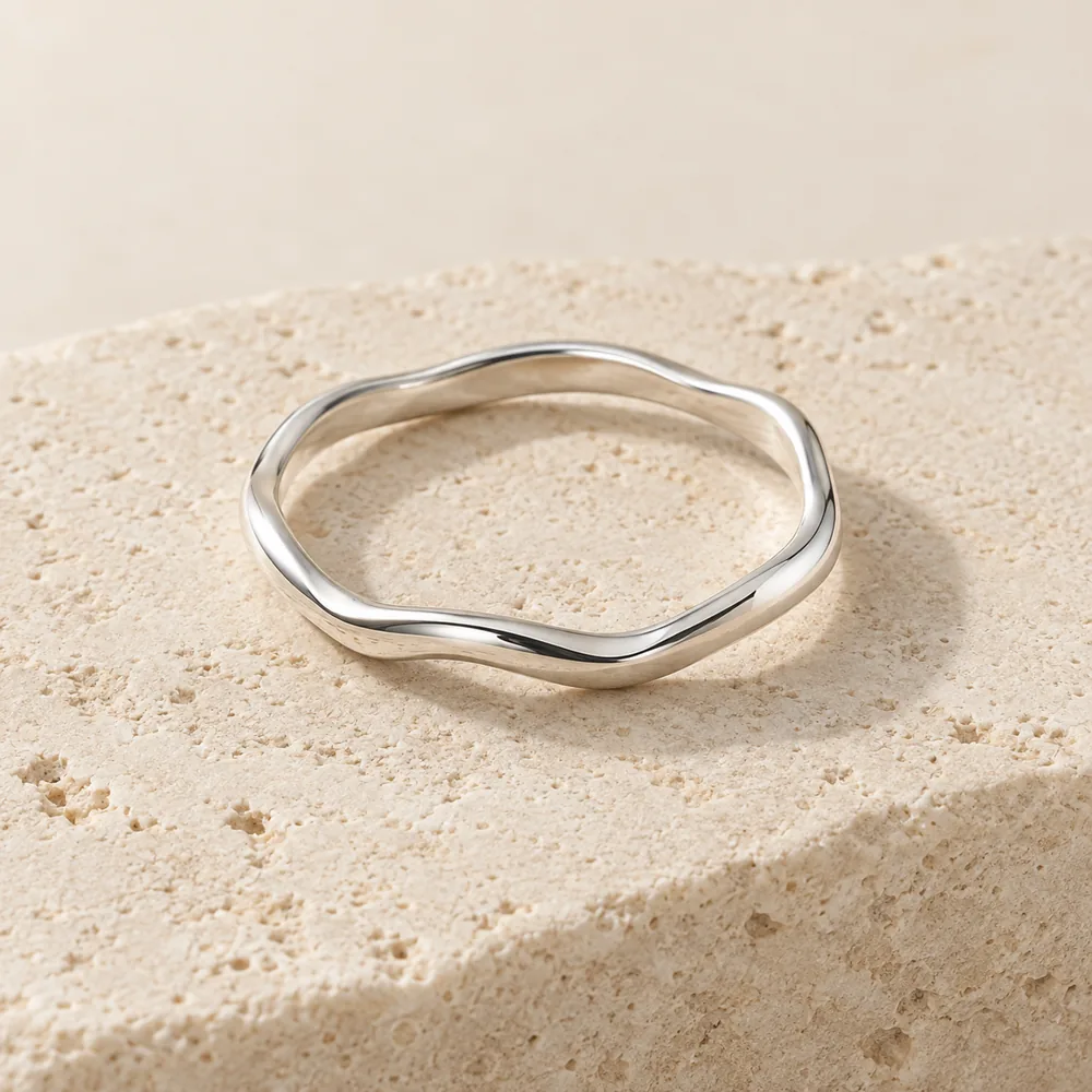Concepto de un anillo plateado de forma orgánica sobre piedra clara